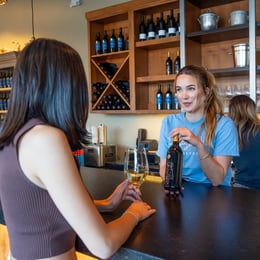 Tasting Room Staff helping young woman with wine tasting