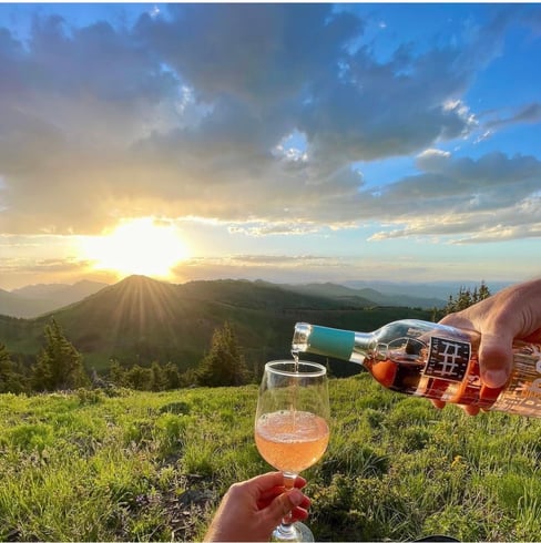 Pouring a glass of Idaho Sparkling Wine in front of a beautiful scene of the sun shining just over the distant mountains